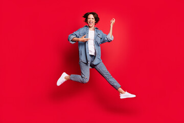 Full size photo of young woman happy positive smile play guitar jump isolated over red color...