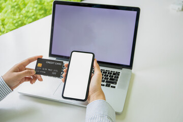 Close up woman hand using credit card and smartphone laptop for buying online shopping