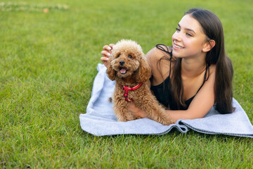 Evening walks. Beautiful girl and her pet, little golden poodle dog strolling in public park, outdoors. Summer time. Sincere emotions. leisure activities concept