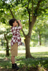 American little boy standing explorer with his paper binoculars in the nature