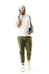 Happy relaxed nerdy hipster style young man walking and talking on the phone. Full length portrait isolated on white background