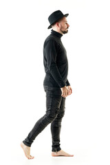 Side view of artist man performer in full black clothes walking barefoot. Full length portrait isolated on white background