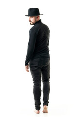 Fototapeta premium Back view of offbeat style man with black clothes and hat walking away looking back thoughtful. Full length portrait isolated on white background