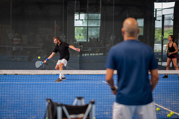 Monitor teaching padel class to man, his student - Trainer teaches boy how to play padel on indoor...