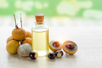 longan fruit with seed is near glass bottle closed by round cap containing oil. Natural remedy with antioxidant and anti-inflammatory properties.