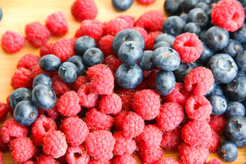 raspberries and blueberries on wooden table
