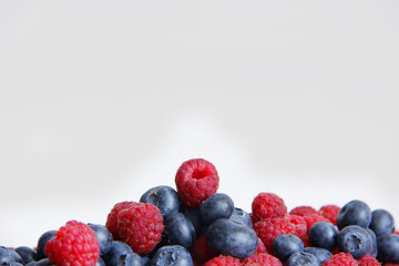 fresh raspberries and blueberries on a white background close-up