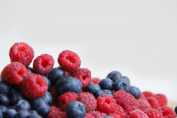 fresh raspberries and blueberries on a white background close-up