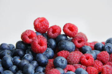fresh raspberries and blueberries on a white background close-up