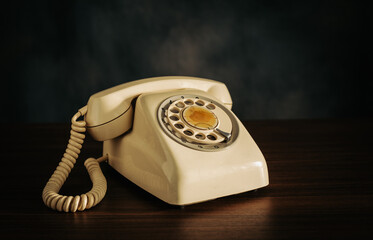Retro old rotating telephone on wood with dark background.