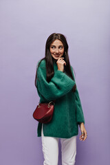 Pretty brunette girl in woolen green sweater and white pants with cross-body stylish bag...
