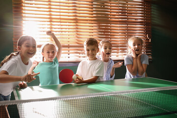 Cute happy children playing ping pong indoors