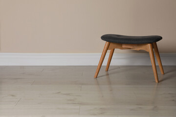 Stylish stool near beige wall indoors. Space for text