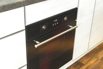 Closed electric oven in modern wooden interior kitchen design background photo