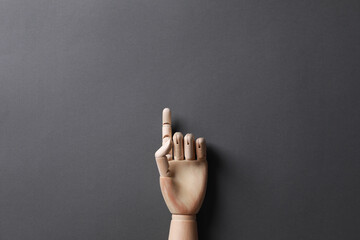 Wooden mannequin hand on grey background, top view