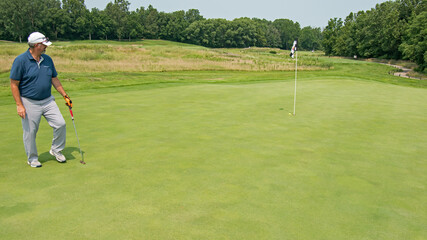 Golfer watches his putt reach very near the pin.
