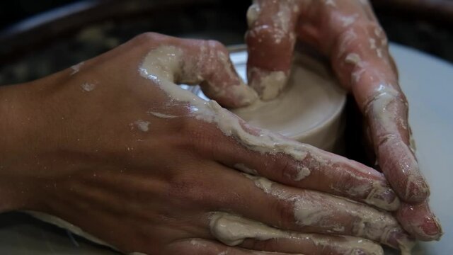 Potter makes ceramic dishes on a twisted potter's wheel. Close-up of Potter at work. Handicraft, craft. White clay
