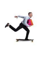 Late for meeting. Portrait of young Caucasian man, office worker rides on skateboard isolated on...