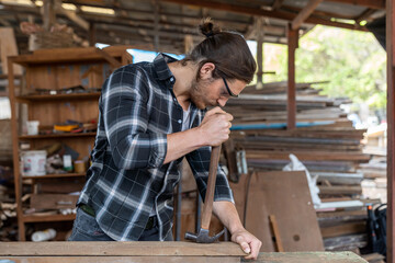 Male carpenter using hammer remove nail from wooden board at the carpentry workshop. Joiner working with hammer remove nails on wooden plank
