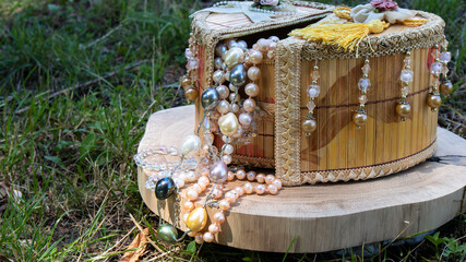 Various  multi colored shiny pearl necklaces hanging from a beautiful handmade vintage jewelry box....