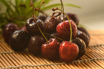 Cherry berries covered with water droplets. The berries are on a bamboo substrate. Close-up. Different colors of red. 