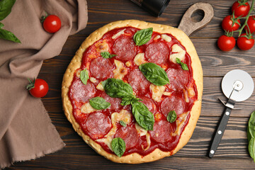 Pita pizza with pepperoni, cheese, basil and tomatoes on wooden table, flat lay
