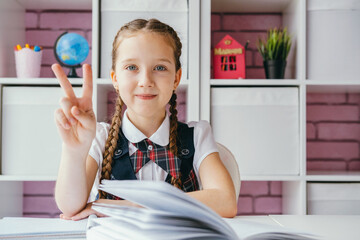 Portrait beautiful positive little schoolgirl sitting at her desk. Back to school concept.