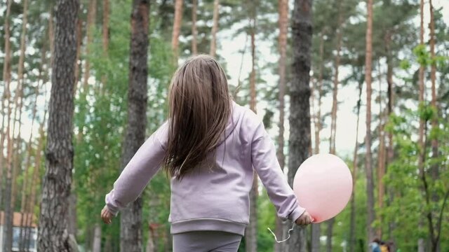 pretty girl tween teenager in purple costume having fun playing with hot air balloons outdoors. holliday, party, birthday, celebration. happy children. slow motion.