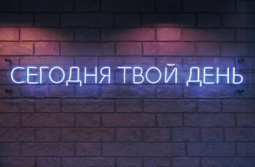 Today is your day. Neon Russian text on dark brick wall.