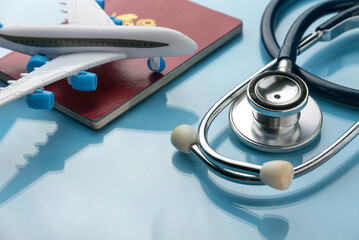 Healthcare,transportation and tourism concept with stethoscope, passport and plane model on a blue...