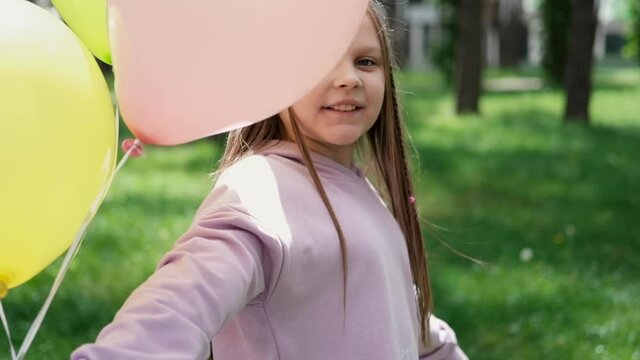 pretty girl tween teenager in purple costume having fun playing with hot air balloons outdoors. holliday, party, birthday, celebration. happy children. slow motion.