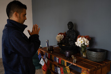 man meditating in his house in front of buddha