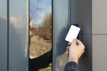 Man opening magnetic door lock with key card outdoors, closeup