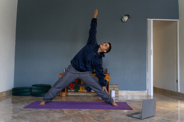 latin man does yoga postures and virtual meditation at home