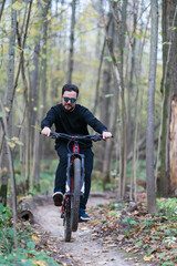 A man making a trick while riding a bycicle in the autumn forest