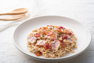 instant noodle carbonara sauce mushroom with bacon in white plate.fusion food