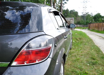 Obraz premium Rear view of the headlights of a gray car against the background of a summer road