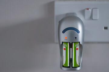 Rechargeable AA Batteries being Charged With a Battery Charger, as Red Light is Illuminated
