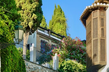 Fototapeta na wymiar Exterior of a carmen, typical house in the Albaicin neighborhood of Granada, with flowers, cypresses and a wooden balcony