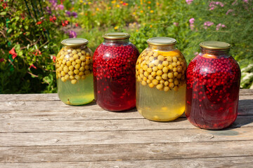 Jars of gooseberry and red currant compote are on a wooden table