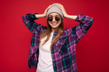 Photo shot of beautiful positive young brunette woman wearing summer casual clothes and stylish sunglasses isolated over colorful background wall looking at camera