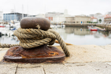 Metal and rusted mooring lock with thick rope loop in close-up