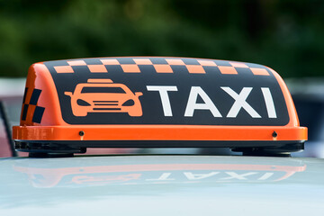 an orange taxi sign stands on the roof of the car