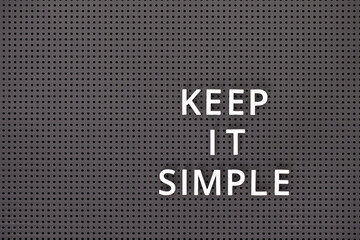 Phrase Keep It Simple spelled out with white letters on gray pegboard