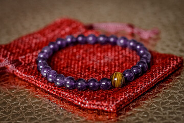 on the golden surface on a linen bag there is a bracelet made of natural stones