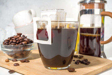 Instant freshly brewed cup of coffee from bag. Trendy variety of drip coffee, on white kitchen table with cups, copy space