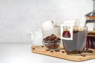 Instant freshly brewed cup of coffee from bag. Trendy variety of drip coffee, on white kitchen table with cups, copy space