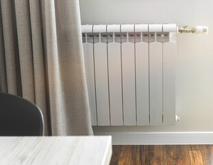 Heating radiator in a bright room with laminated wooden floor