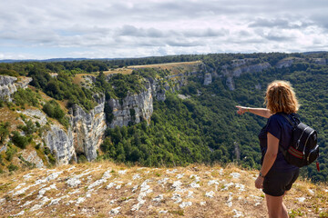 green landscape with a cliff and deep view of a green valley with a person enjoying the views