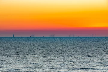 Fototapeten The impressive off shore windpark Luchterduinen. The windmills are in the Noordzee, 23 kilometers from the Dutch coastline between Noordwijk and Zandvoort. On the clear horizon with a beautiful sunset © misign